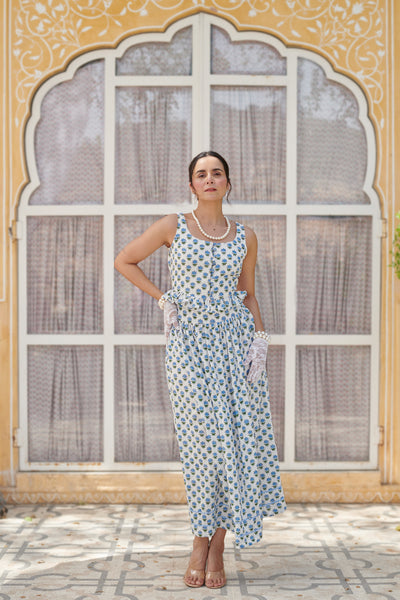Woman in a floral dress standing in front of an ornate window.
